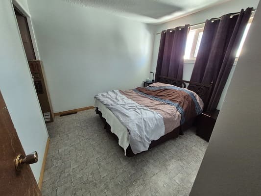 Small bedroom with bed and curtains.