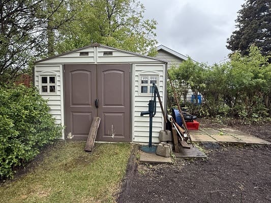 Garden shed with tools and greenery around.
