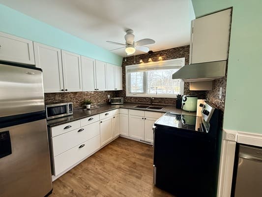 Modern kitchen with white cabinets and appliances.