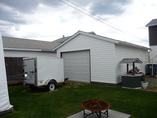 Garage with trailer and fire pit outside.