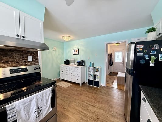Modern kitchen with teal walls and wood floor.