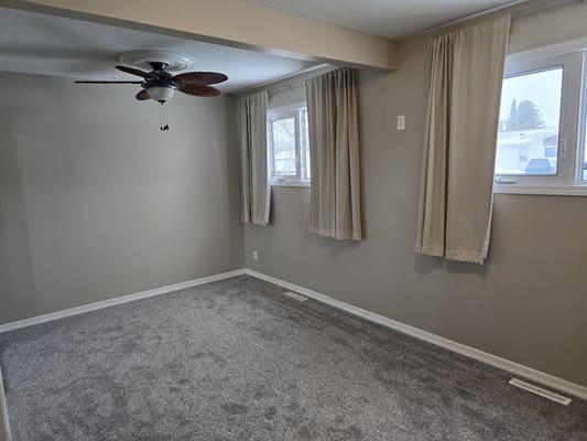 Empty room with carpet and ceiling fan.