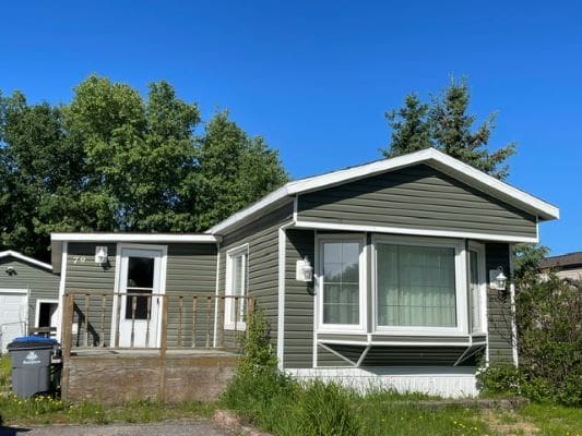 Green manufactured home with front deck