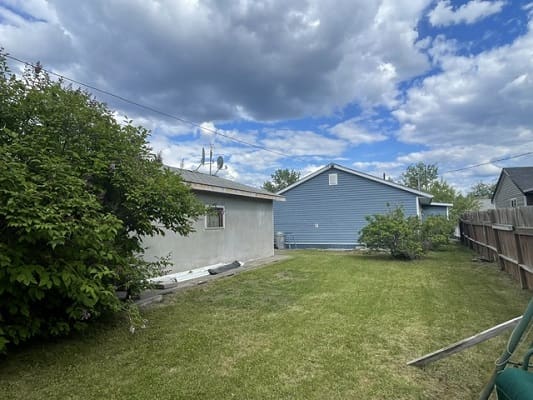 Backyard lawn with garage and cloudy sky