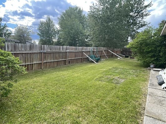 Fenced backyard with lawn and swing frame